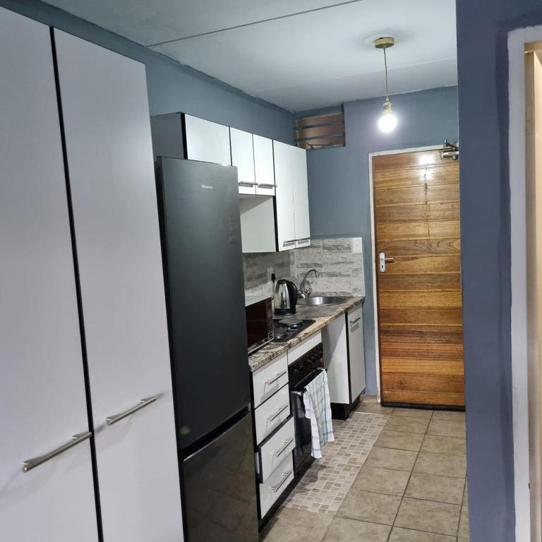 a kitchen with white cabinets and a black refrigerator at Greggs Place at Capital Hill Arcadia in Pretoria