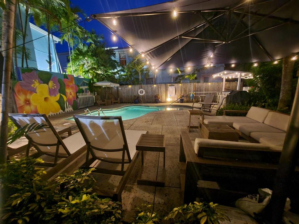 a backyard with a pool with chairs and a couch at Three Duval Street Suites w parking and pool in Key West