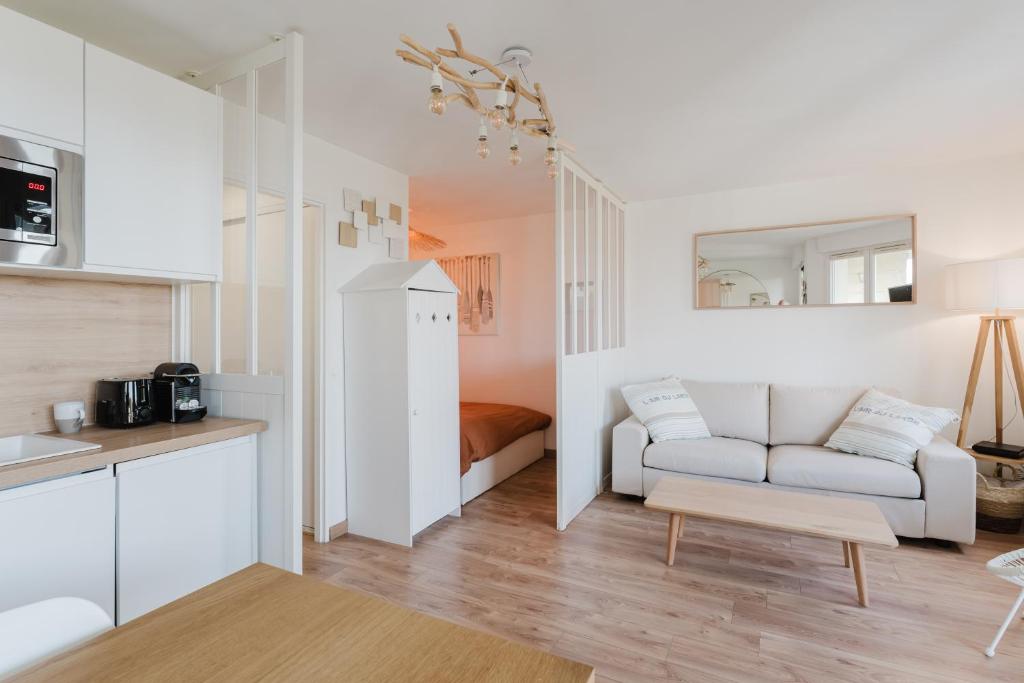 un salon avec un canapé et une cuisine dans l'établissement Bord de mer, Jardin privé, 100 m de la mer, à Tourgéville
