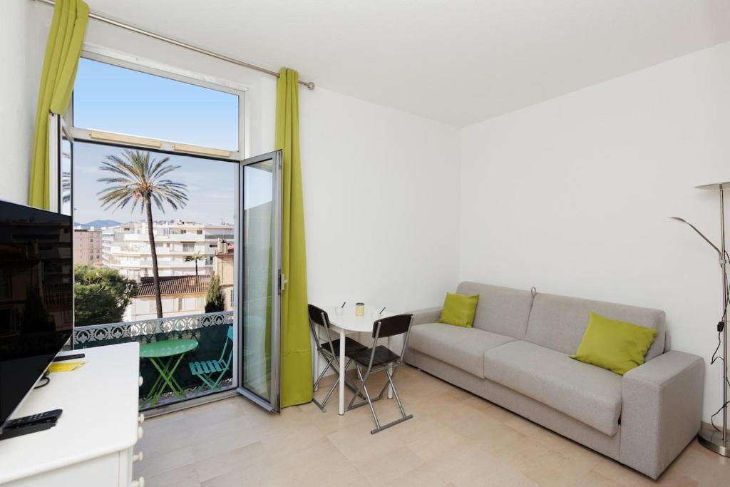 - un salon avec un canapé, une table et une grande fenêtre dans l'établissement Studio Rimbaud - Festival-Center-Clim-Wifi, à Cannes