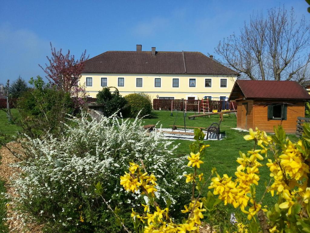 a large white house with a yard with yellow flowers at Familienbauernhof Strassbauer in Steinakirchen am Forst