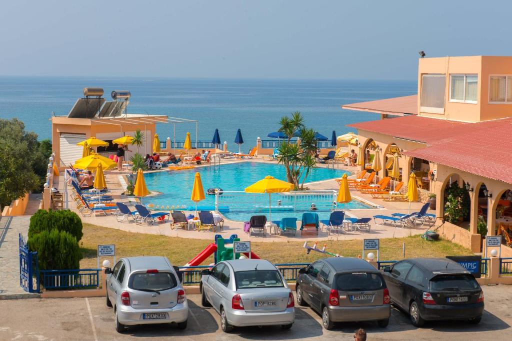 eine Gruppe von Autos, die vor einem Pool geparkt werden in der Unterkunft Palm Bay Hotel in Pefki Rhodes