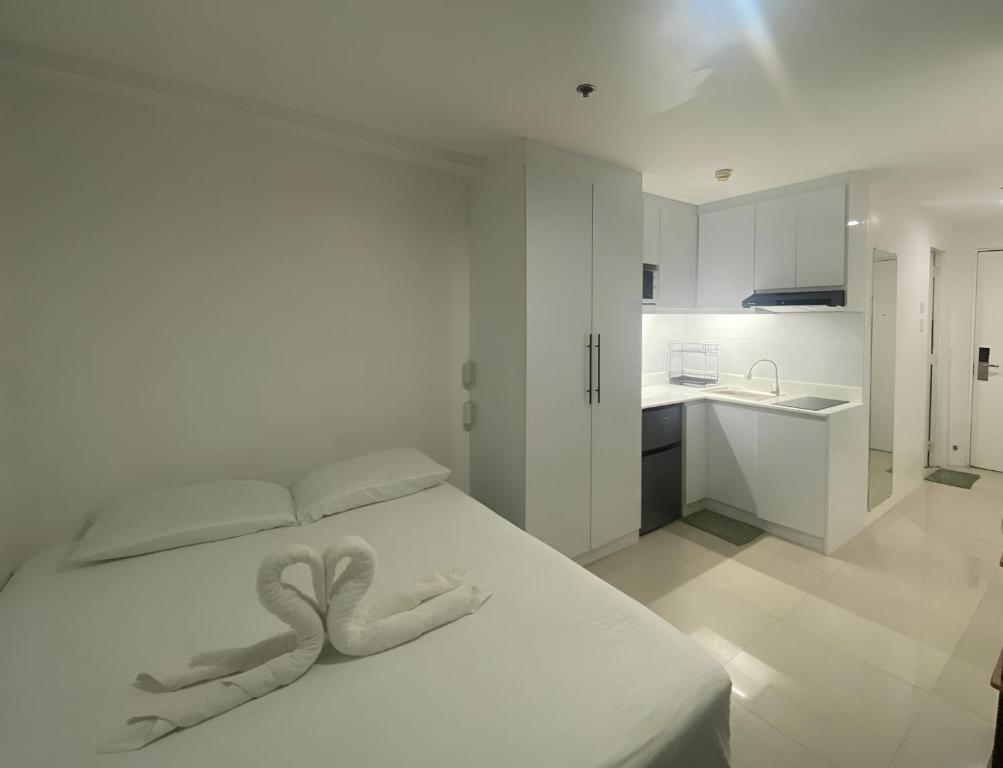 a white bedroom with a bed and a kitchen at Cityscape Tower 2 Condo in Midtown Cebu in Cebu City
