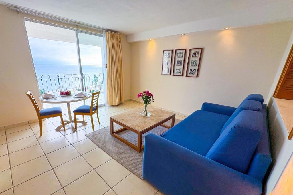 een woonkamer met een blauwe bank en een tafel bij Suite with panoramic ocean views & balcony! in Puerto Vallarta