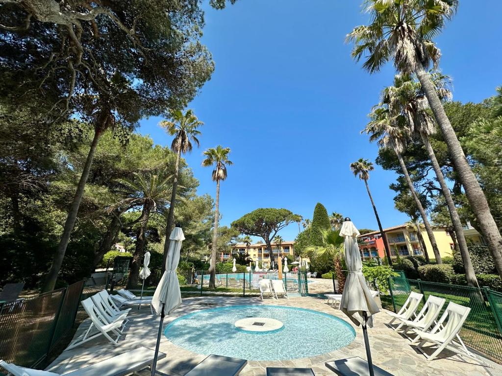 a pool with chairs and umbrellas and palm trees at BADINE BEACH 5 personnes vue jardin avec climatisation in Hyères