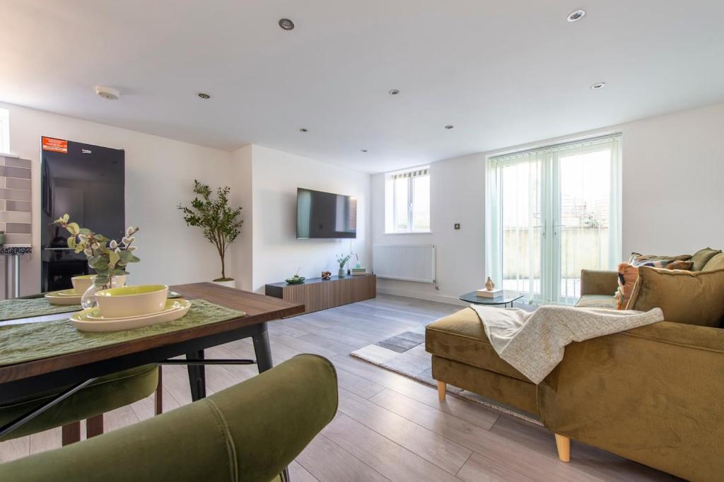 a living room with a couch and a table at The Green Haven-Cozy luxury flat in Crayford in Slades Green