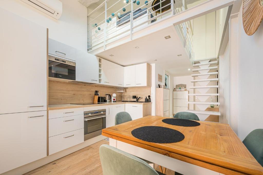 a kitchen with white cabinets and a wooden table and chairs at Le Duplex in Villefranche-sur-Mer