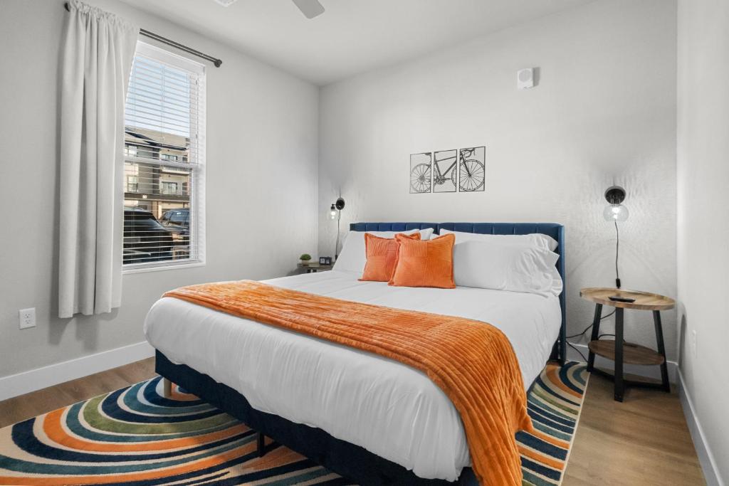 a bedroom with a bed with orange pillows and a window at Relax In Style Cozy 1br W Pool, Gym & Free "p" in Rogers