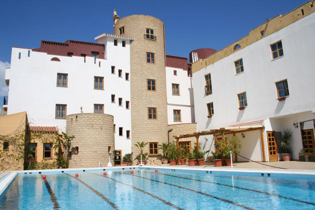ヴィッラッジョ・モセにあるHotel Tre Torriの2つの城の前にスイミングプールがあるホテル
