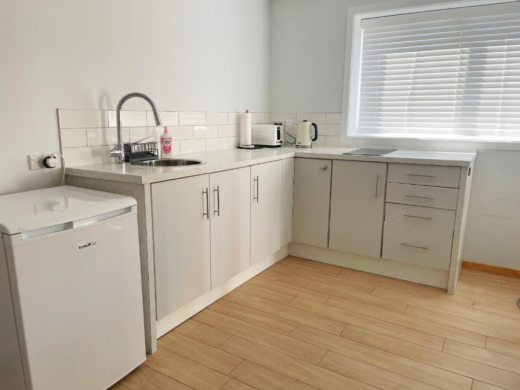 Una cocina con gabinetes blancos y un fregadero. en Living Oasis, en Auckland