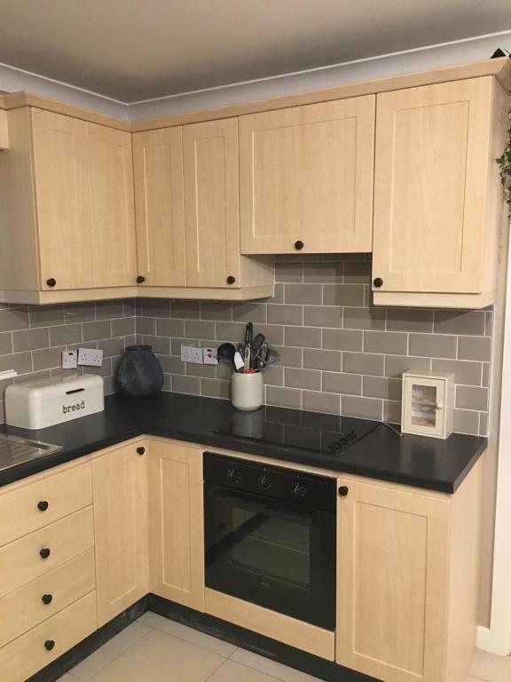 a kitchen with wooden cabinets and black counter tops at Sruthan na Teorainn in Carraroe