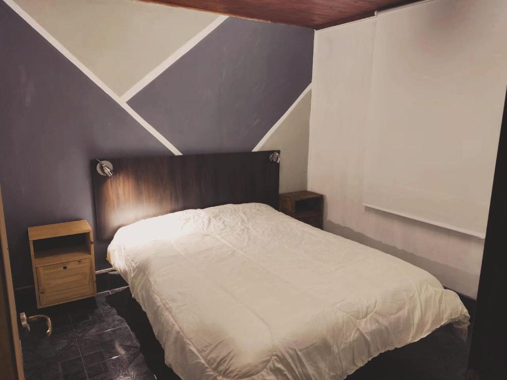 a bedroom with a white bed with a wooden headboard at Cabaña DON LITO in Ciudad Lujan de Cuyo