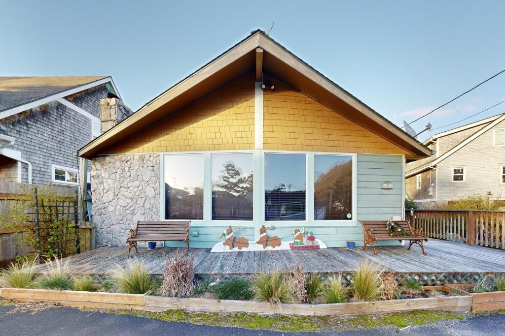 a house with two benches on a deck at Darrs Beach Cottage in Neskowin