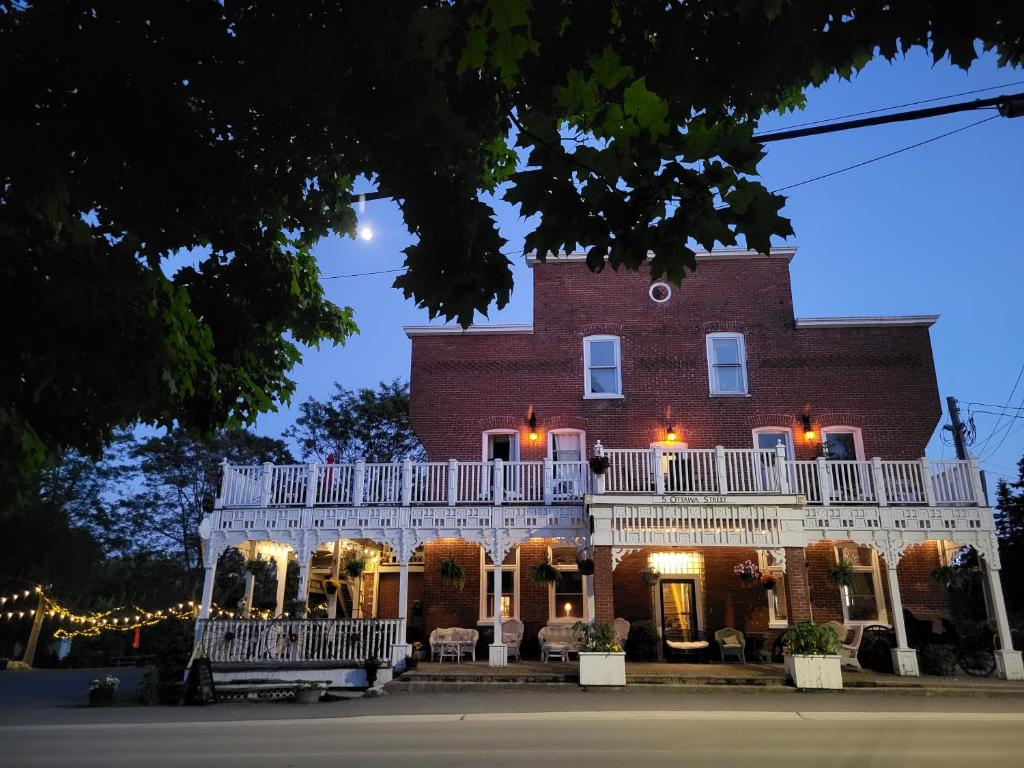 a large red brick building with a white balcony at The Tamworth Hotel, Tamworth ,Ontario, Canada in Tamworth