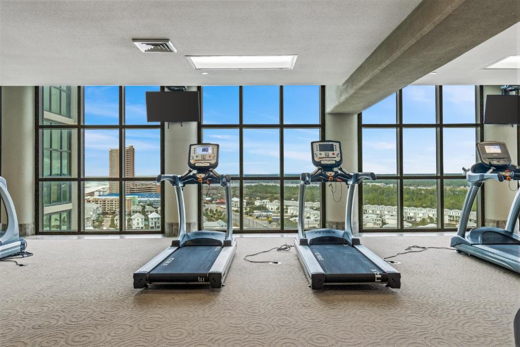 une salle de sport avec des machines cardio et de grandes fenêtres dans l'établissement The Oasis at Orange Beach 1707, à Orange Beach