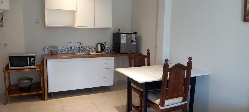 a kitchen with white cabinets and a table and a microwave at Domus B1 in Posadas