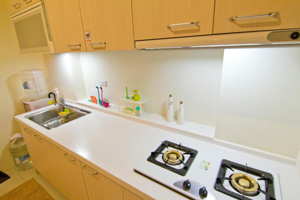 a kitchen with a stove top oven next to a sink at 充電樁 羅東木村電梯民宿Luodong Tree BnB 雲朵朵二館 免費洗衣機 烘衣機 星巴克咖啡豆 國旅卡特約店 in Luodong