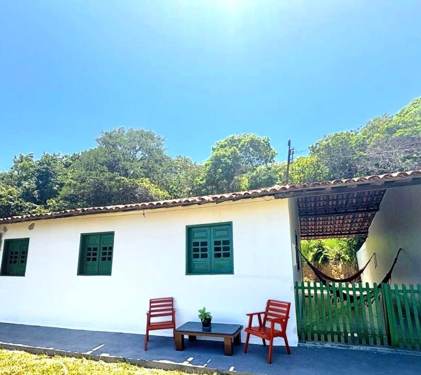 a white house with two red chairs and a table at Paraíso Escondido Beach House! in Goiana