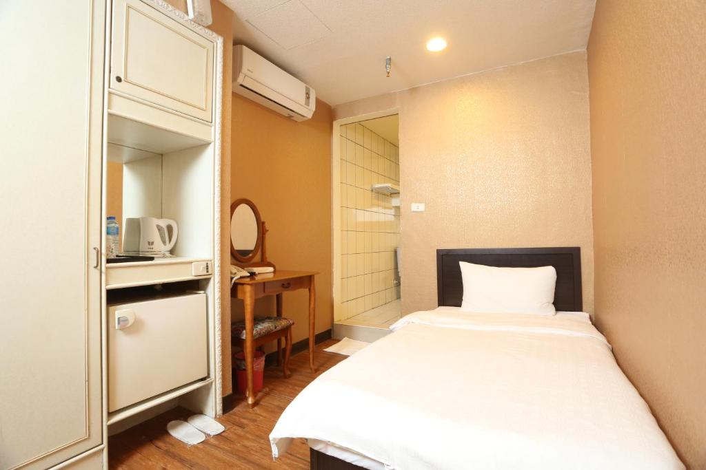 Banciaoking Hotel في تايبيه: غرفة صغيرة بها سرير وخزانة