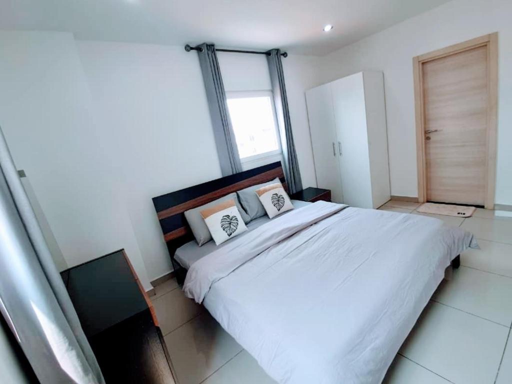 阿克拉Chic 1BR Apt with Pool, High-speed Internet at The Gallery, 10 mins from Airport, 5mins from Major Restaurants and Malls的卧室配有一张带两个枕头的大白色床
