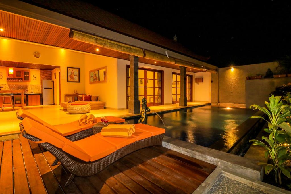 a swimming pool with an orange table and chairs in a house at Taman Amertha Villas by Maha Bali in Seminyak