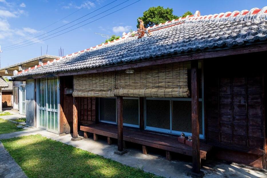 un vieux bâtiment avec un banc devant dans l'établissement 猫宿 Muribushi-inn, à Motobu