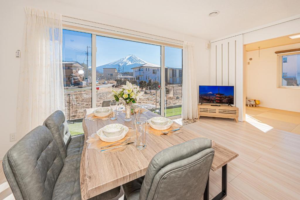a dining room with a table and chairs and a large window at New Open! Collab House 富士山眺望 送迎無料 BBQ 器具無料貸出 in Fujikawaguchiko