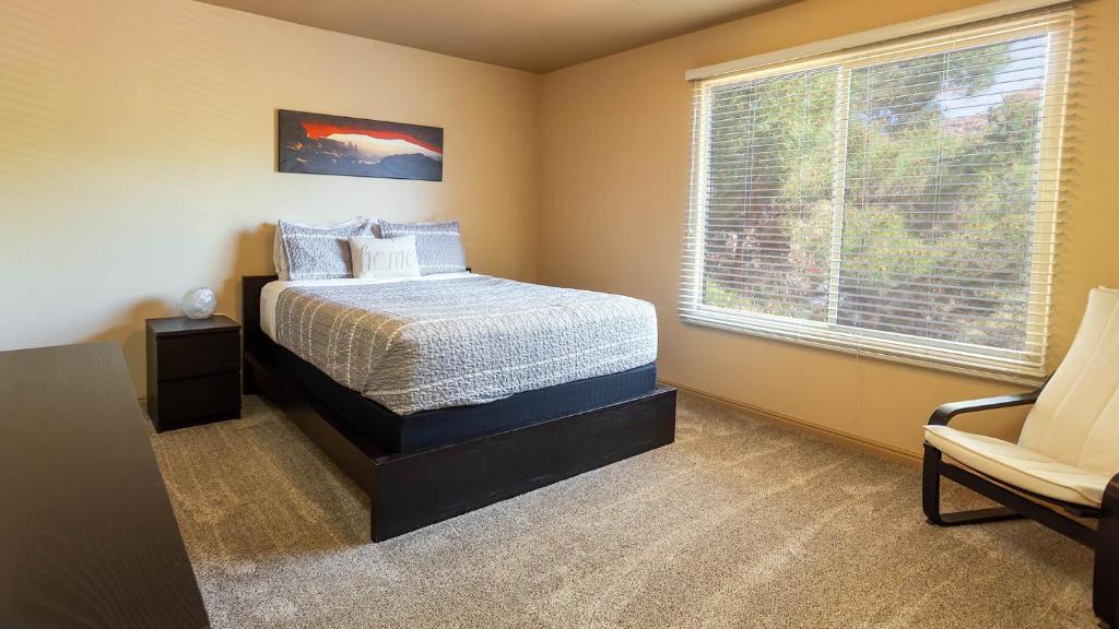 ein Schlafzimmer mit einem Bett, einem Fenster und einem Stuhl in der Unterkunft Kanab Townhome Pool and Hot Tub Pets OK in Kanab
