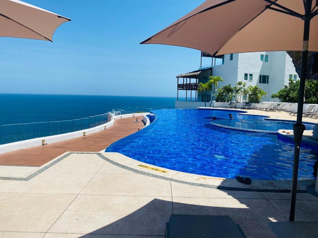 einen Pool mit Sonnenschirm am Meer in der Unterkunft Bello departamento con vistas al mar in Acapulco