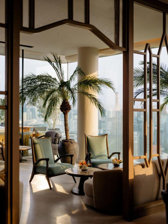 a lobby with a palm tree and chairs and a table at Dusit Thani Bangkok in Bangkok