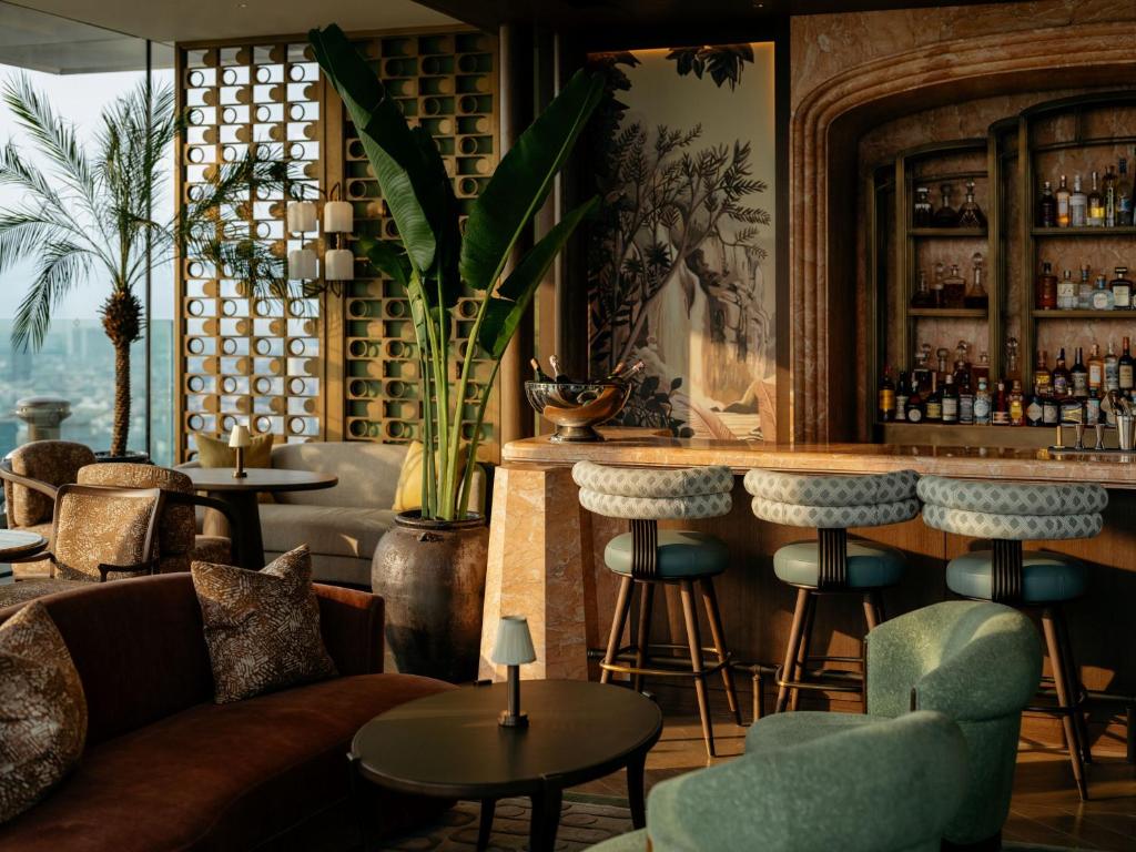 a bar with a couch and chairs and tables at Dusit Thani Bangkok in Bangkok