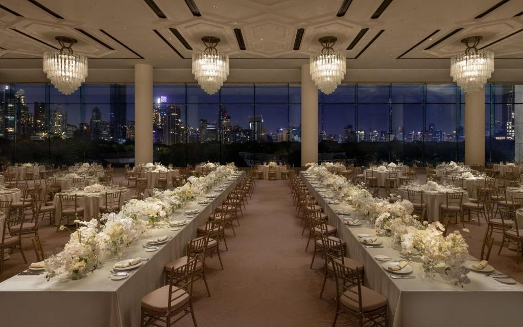 A banquet hall set for a large formal dinner with a nighttime skyline view.