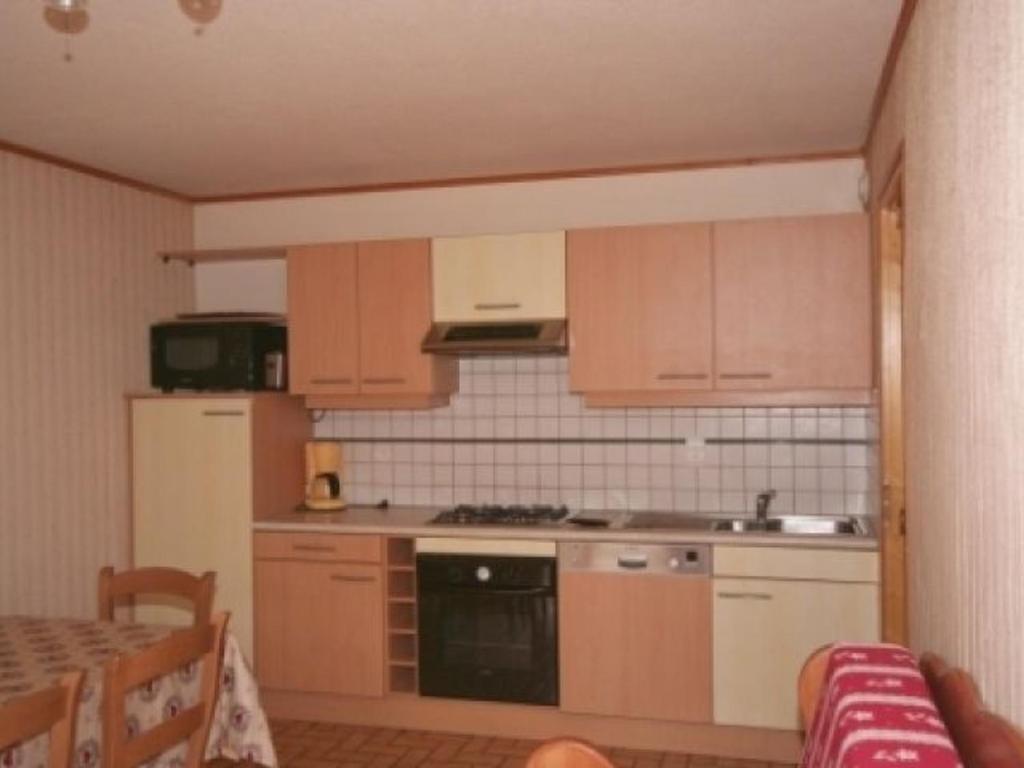 une cuisine avec des armoires en bois et un four à plaques de cuisson dans l'établissement Appartement Châtel 5 Pers, Terrasse, Animaux admis - FR-1-676-207, à Châtel