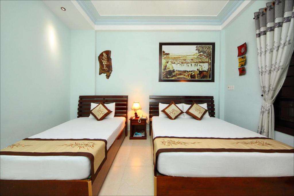 2 camas en una habitación con paredes azules en Dong Nguyen Riverside Homestay, en Hoi An