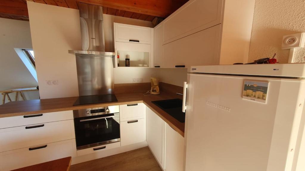 une cuisine avec des armoires blanches et un réfrigérateur blanc dans l'établissement Duplex apartment with sea view, à Carnac