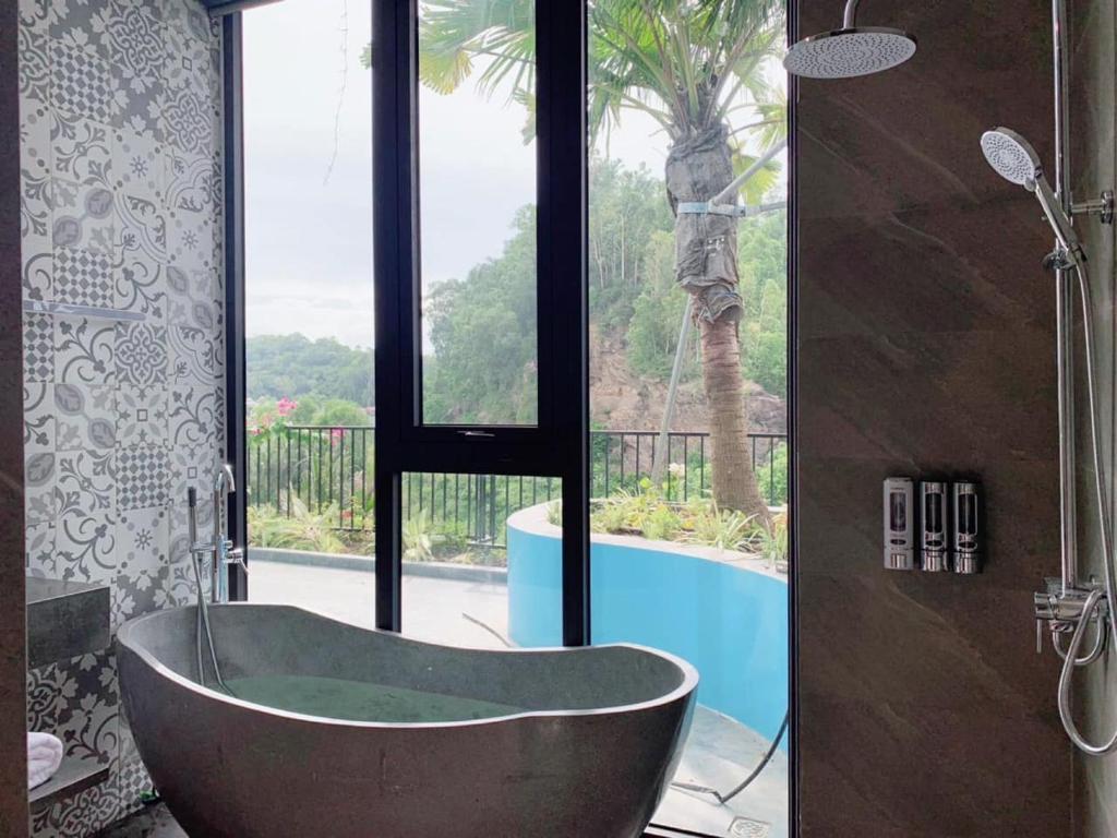 a bathroom with a tub and a view of a pool at Villa Ốc Biển Xanh - Flamingo Hải Tiến in Thanh Hóa