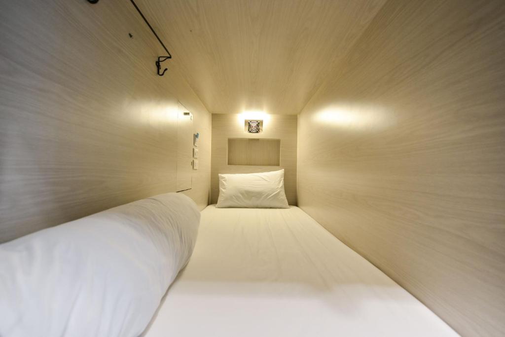 una piccola camera con un letto bianco di The Cube Hostel Silom a Bangkok