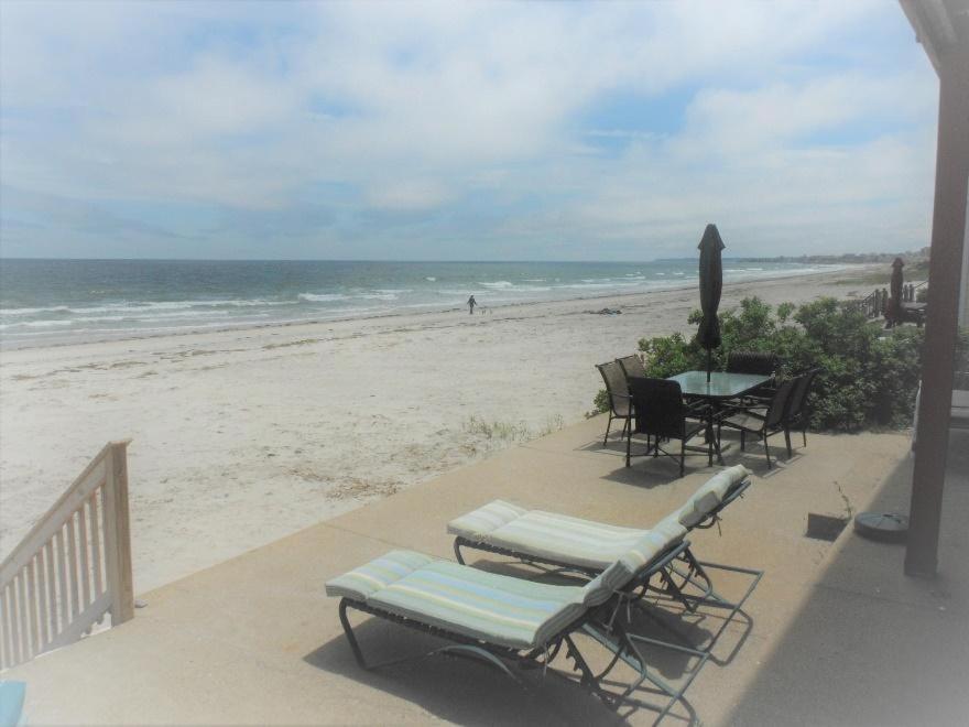een patio met een tafel en stoelen op het strand bij Sea Breeze W007 Wonderful Beachfront Oceanfront property for the whole family 1897 in Wells