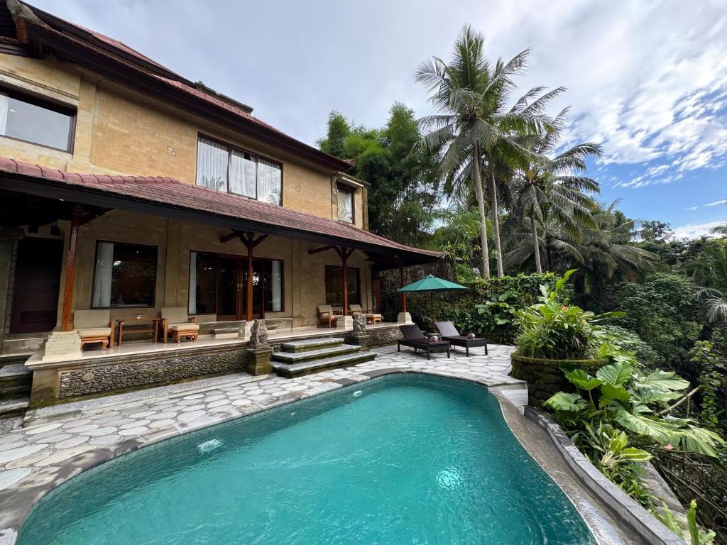ウブドにあるSakti Garden Resort & Spaの家の前にスイミングプールがある家