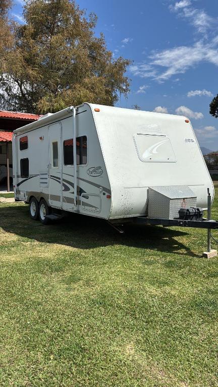 a white trailer is parked in a field at Casa Rodante Roca Azul in Jocotepec