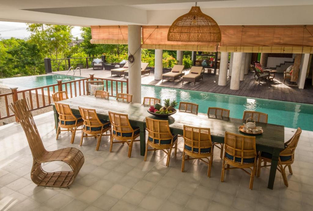 a patio with a table and chairs and a pool at Adila Bali in Uluwatu