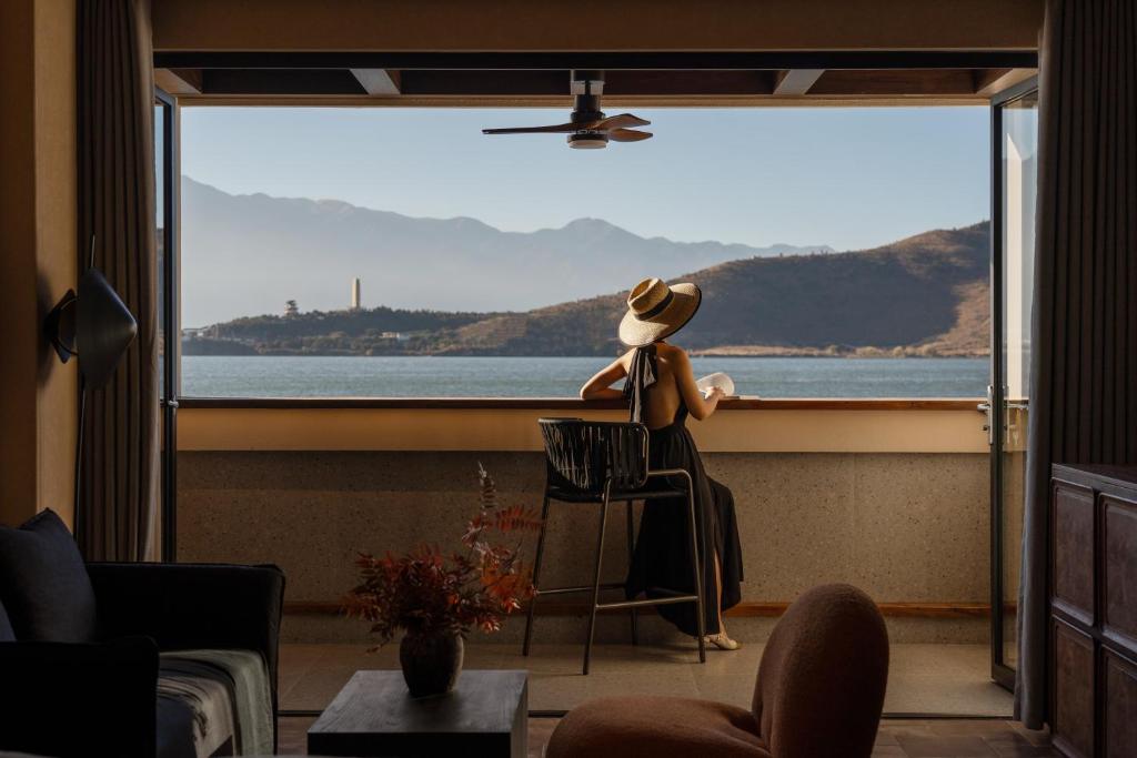 una persona sentada en una silla frente a una ventana en Dali Antu Sky Seascape Hotel, en Dali Airport