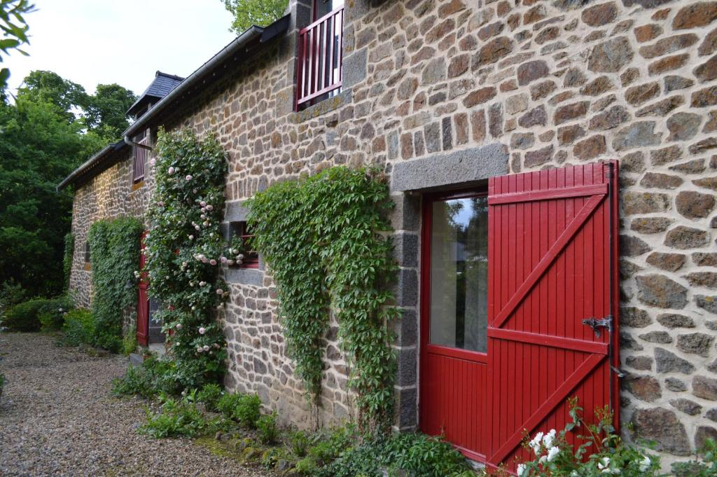 una puerta roja en el lateral de un edificio de ladrillo en Le Domaine, en Les Iffs
