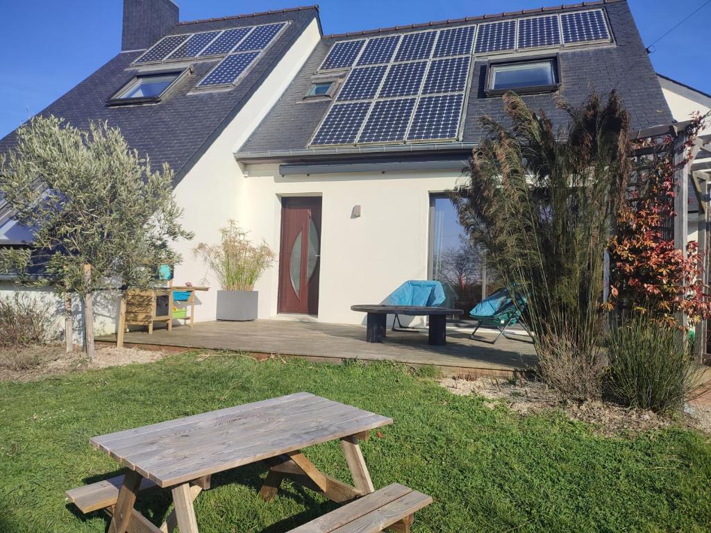 - une table de pique-nique devant une maison avec des panneaux solaires sur le toit dans l'établissement Maison proche mer, à Lancieux