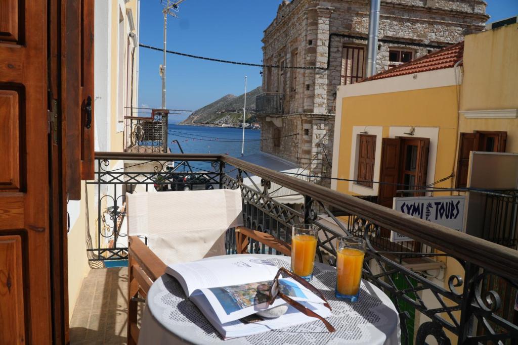 a table on a balcony with a book and orange juice at Antoni's Symi Home in Symi