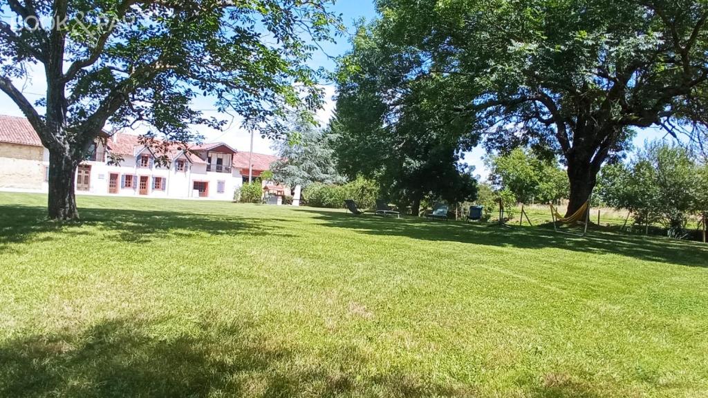 un champ d'herbe planté d'arbres devant une maison dans l'établissement Gîte - Relais de Soubeille - Nature - Comminges Pyrenees, à Boulogne-sur-Gesse