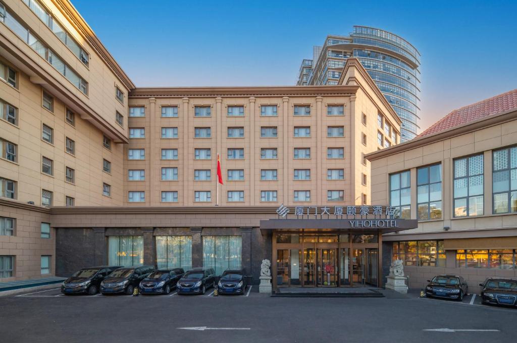 un grande edificio con auto parcheggiate di fronte di Beijing Xiamen Mansion Yihao Hotel a Pechino