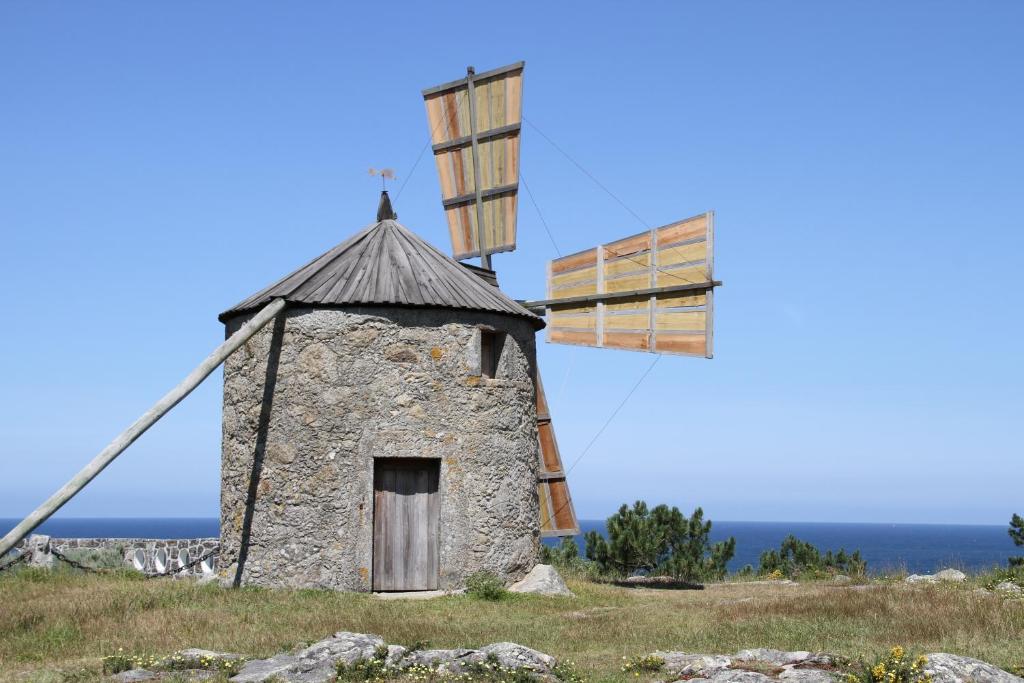 een windmolen op een heuvel met de oceaan op de achtergrond bij Casa do Farol in Viana do Castelo