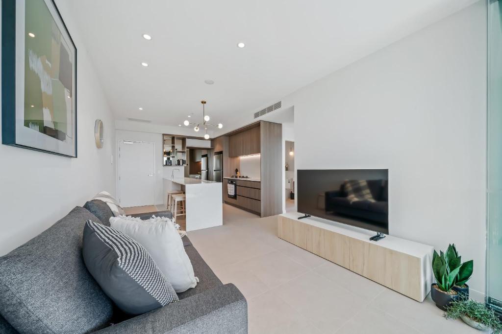a living room with a gray couch and a television at Brand new Luxurious 1 Bedroom Perth CBD in Perth
