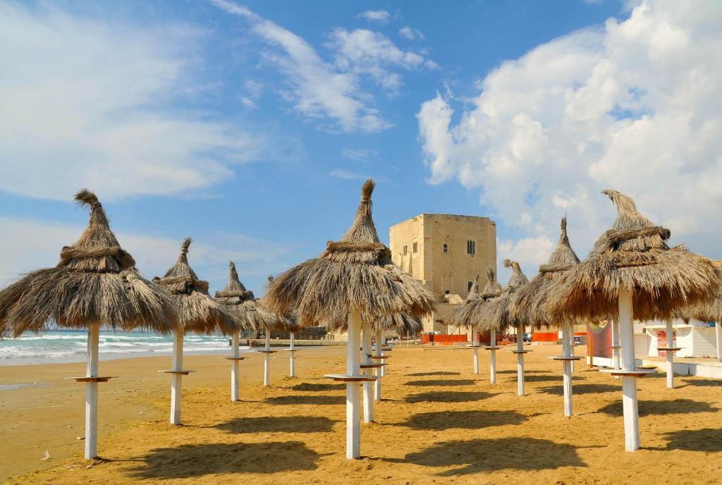 rząd słomianych parasoli na plaży w obiekcie Vacanze Romantiche a Modica w mieście Modica